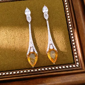 Vista dettagliata di lussuosi orecchini a goccia placcati oro 18 carati con pietre arancio.