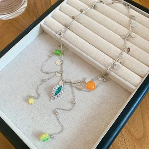Detailed view of a silver-toned necklace with colorful beads and a leaf-shaped pendant.