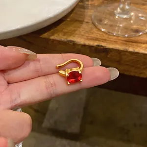 Primo piano di ear cuff placcato oro 18k con una vibrante pietra di zircone rosso