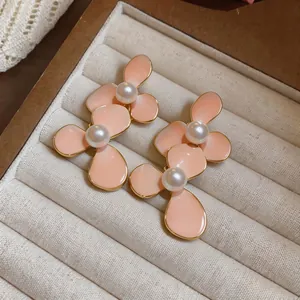 Gedetailleerde weergave van elegante perzikkleurige bloemenoorbellen met parels.