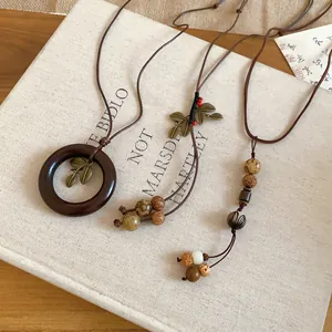 Close-up of vintage ethnic necklaces with wooden rings and metal leaves on a book.