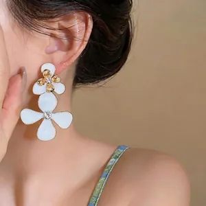 Pendientes colgantes de flores en esmalte blanco de estilo francés usados por modelo