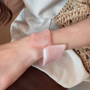 Primer plano de un brazalete de resina rosa con diseño geométrico irregular en la muñeca