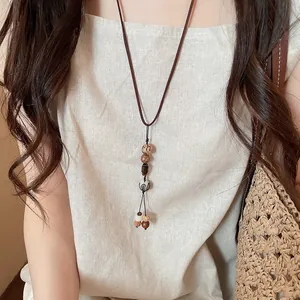 Close-up of vintage ethnic long sweater necklace with multi-patterned beads on model