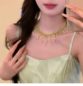 Détail d'un collier de style Mori fait main avec perles vertes et breloques fleurs roses