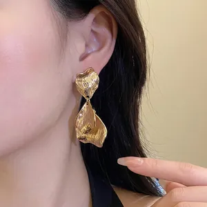 Elegant vintage gold metal crumpled petal drop earrings displayed on a female model