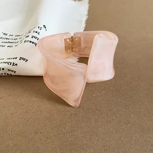 Vista detallada de un brazalete de resina rosa jaspeada con forma geométrica única