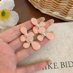 Detailopname van perzikkleurige emaille bloemoorbellen met een elegante parel in
