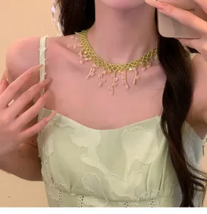 Détail d'un collier de perles fait main avec fleurs roses et mailles vertes délicates
