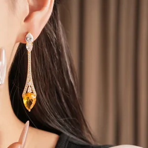 Primo piano di orecchini a goccia placcati oro 18 carati con zircone giallo.