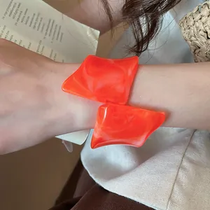 Primer plano de un brazalete geométrico irregular de resina naranja vibrante