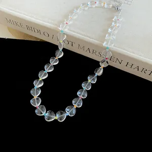 Detail of clear heart-shaped beaded necklace with colorful spacers on black background.