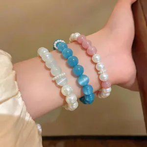 Primo piano di tre braccialetti colorati in occhio di gatto e perle su un polso.