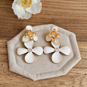 Primer plano de elegantes pendientes de flores en esmalte blanco de estilo francés.