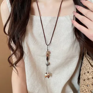 Detail shot of a vintage ethnic style beaded necklace worn on a natural linen top.