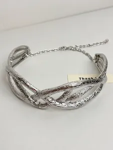 Detailed view of silver pleated cross intertwined necklace with textured metallic finish