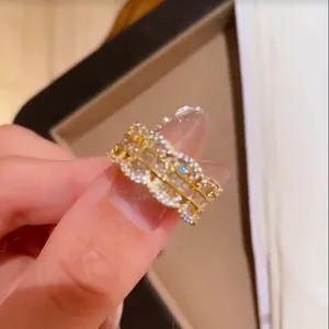 Primo piano di un anello dorato retrò con zirconi brillanti e bordi smerlati fini.