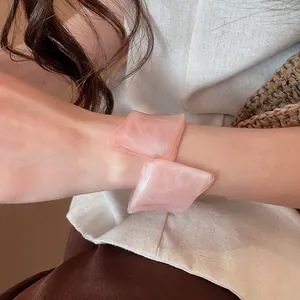 Primer plano de un brazalete de resina rosa geométrico irregular en una muñeca