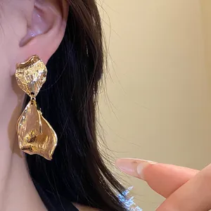 Close-up of elegant gold metal wrinkled petal earrings with premium texture finish.
