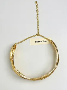 Close-up detail of a gold metallic twisted choker necklace with textured bark finish