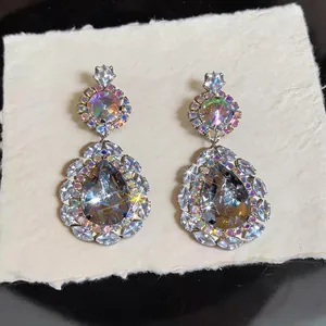 Detailed view of ornate teardrop crystal earrings with silver needles and halo design.