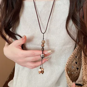 Close-up of retro ethnic long necklace with wooden beads and earthy tones on linen dress