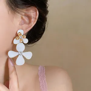Primer plano de elegantes pendientes de flores de esmalte blanco con diamantes