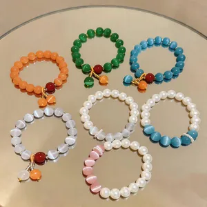 Dettaglio di eleganti braccialetti di perle occhio di gatto su una superficie a specchio