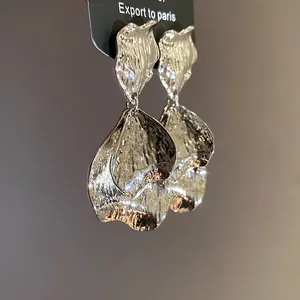 Detail shot of vintage silver metal earrings with a wrinkled petal design and texture.