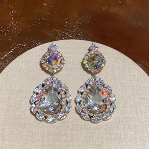 Close-up detail of elegant palace-style waterdrop earrings with sparkling crystals on a stand.