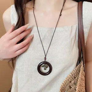 Vintage ethnic style wooden ring necklace with leaf pendant on model wearing linen