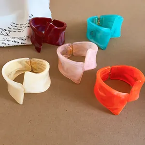 Detalle de cinco pulseras de resina geométricas irregulares en colores vivos con efecto mármol