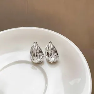 Détail gros plan de boucles d'oreilles créoles en argent avec sertissage de zircons