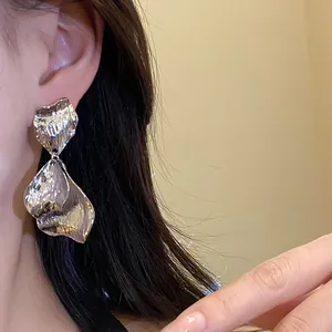 Detailed close-up showing vintage silver metallic wrinkled petal earrings on a female model