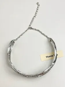 Detailed close-up of a silver metal pleated wrap necklace with textured sculptural design