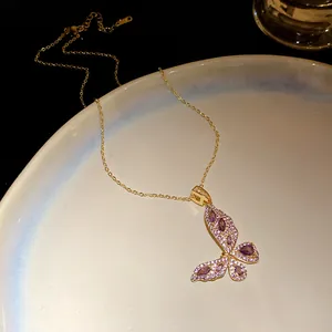 Detailed macro view of gold butterfly pendant inlaid with purple and white zircon.