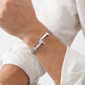 Detailopname van gevlochten roestvrijstalen herenarmband met gebogen spijkerplaat op pols.