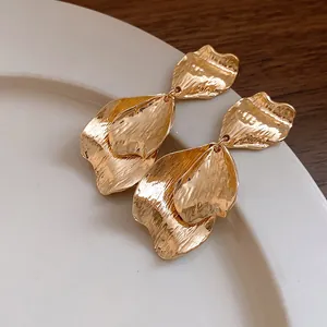 Detail shot of golden metal earrings with unique wrinkled petal texture design