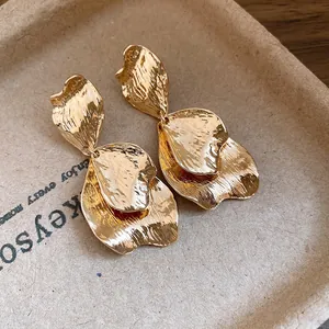 Close-up detail of vintage gold metal earrings featuring artistic wrinkled petal design