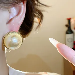 Detail van een grote vintage parelknopoorbel met 14K gouden plating op het oor.