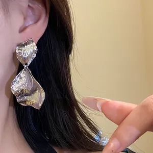 Close-up detail of silver wrinkled petal earrings with hammered metallic texture.