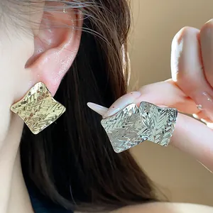Close-up detail of geometric diamond textured earrings in elegant gold and silver tones