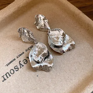 Macro view of vintage silver metallic wrinkled petal earrings with unique textured finish