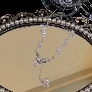 Elegant silver necklace with sparkling crystal leaf and pearls on a mirror tray.