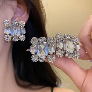 Detailansicht funkelnder quadratischer Strass-Ohrclips an einem asiatischen Modell.