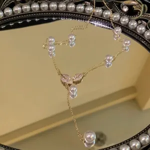 Elegant gold necklace with crystal leaf pendant and pearl tassel drops on mirror display.