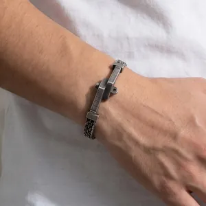 Detailopname van een vintage roestvrijstalen gevlochten armband met punk nagelplaat voor heren