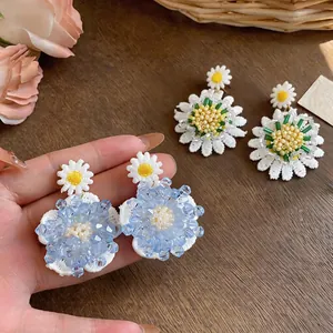 Vista detallada de pendientes de flores margarita hechos a mano con perlas