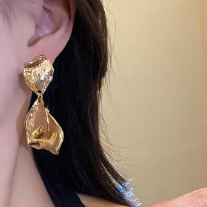 Detailed close-up showing the vintage wrinkled texture of gold metal petal earrings