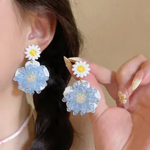 Vista detallada de elegantes pendientes de flores de cristal azul con agujas de plata.